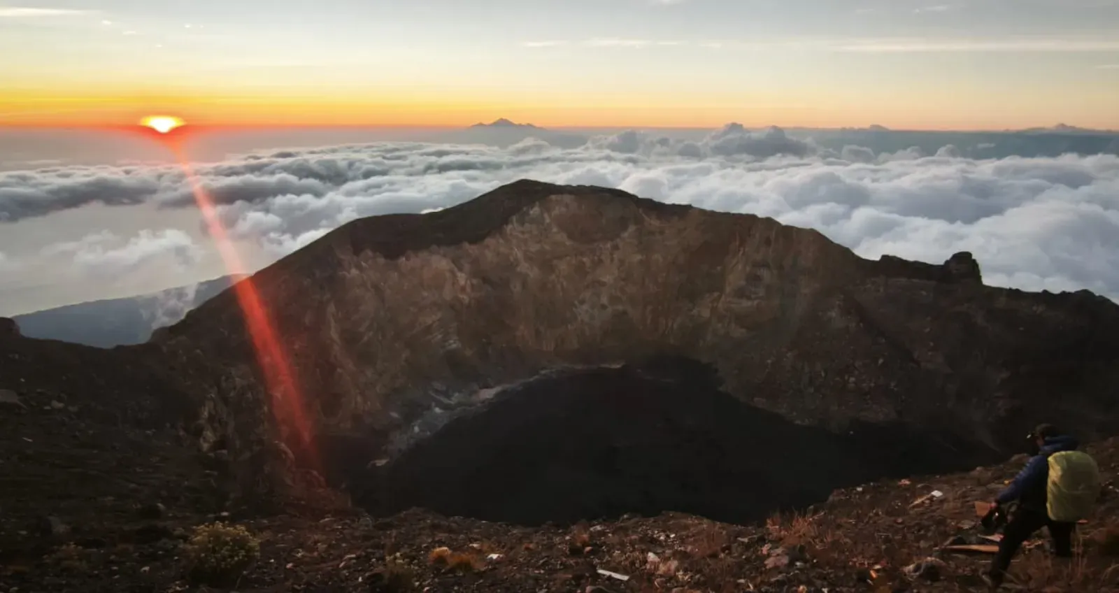 Trekker walking a volcanic mountain trail toward the 3142 m peak