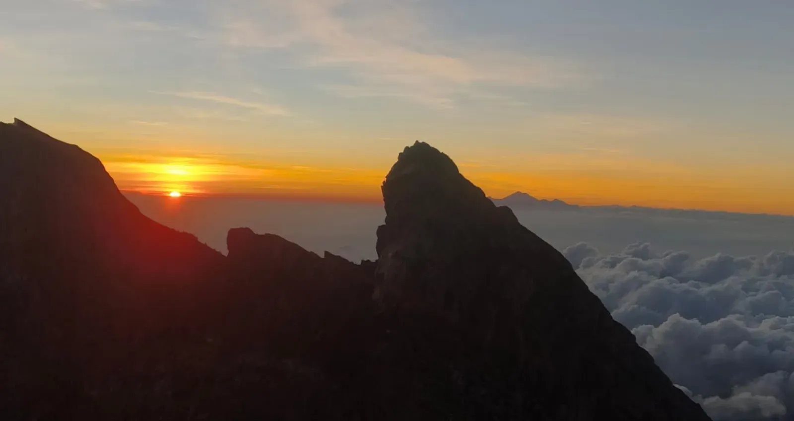 Mount Agung sunrise over a rocky ridge above the clouds