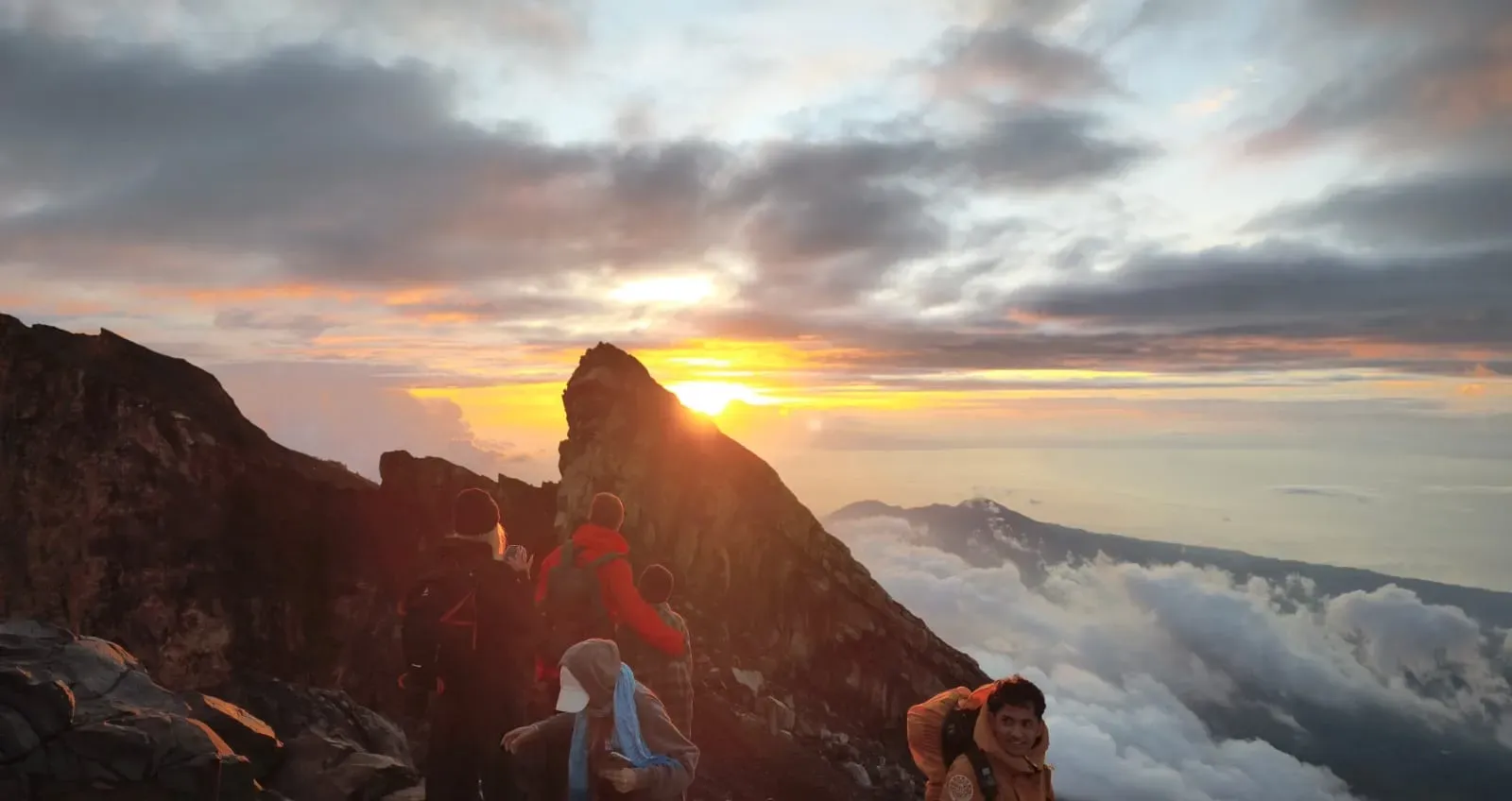 Trekkers and a local guide watching sunrise on the Mount Agung ridge