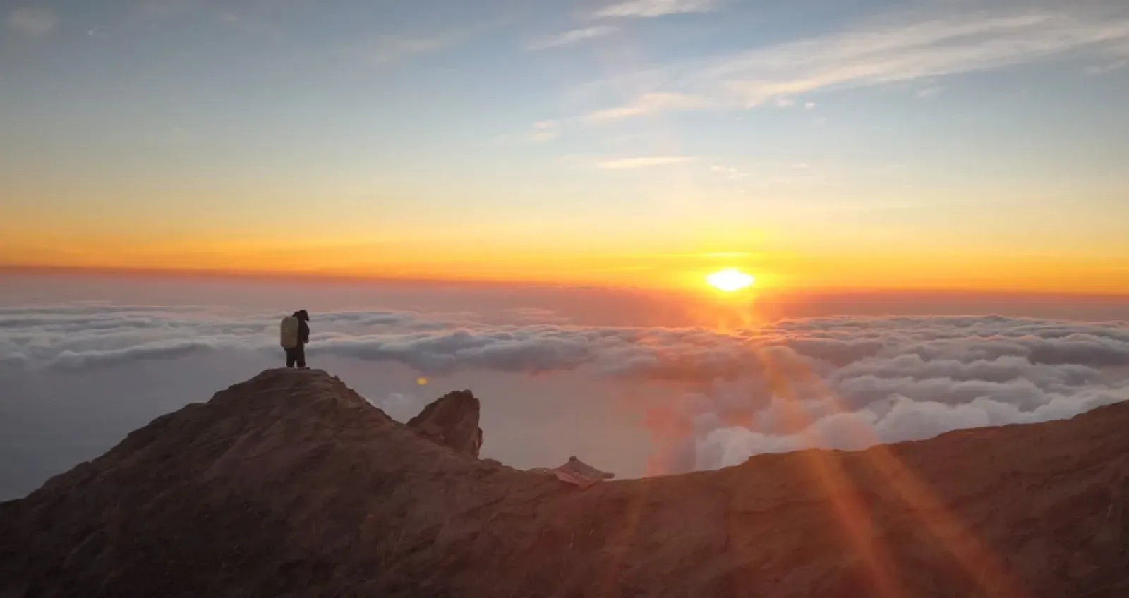 Hiker with a backpack on a Mount Agung ridge at sunrise