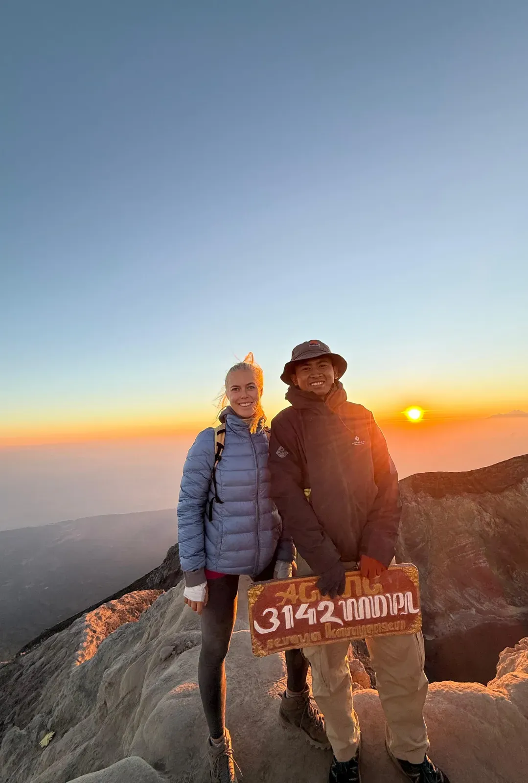 Local guide and guest holding the Agung 3142 MDPL sign at sunrise