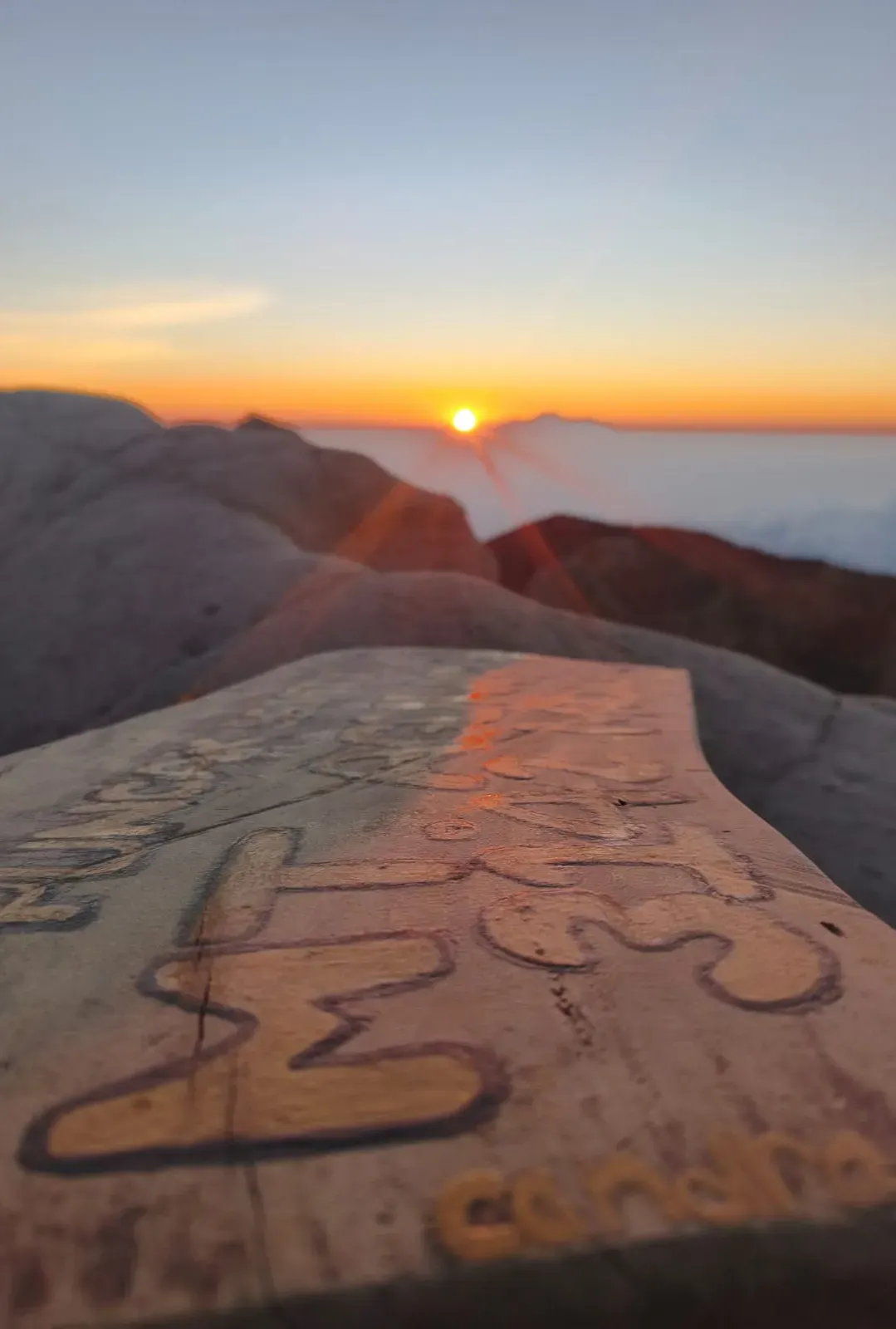 Sunrise over Mount Agung rocks with a carved wooden sign in the foreground