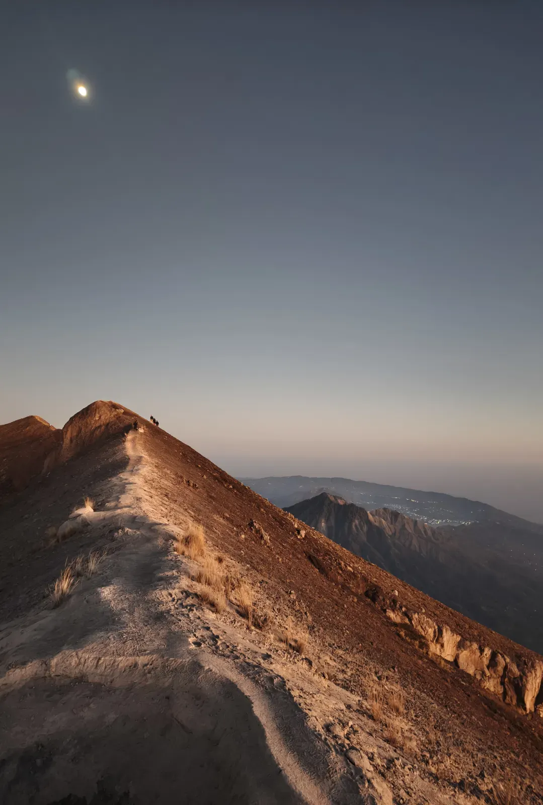 Narrow ridge trail on Mount Agung under a pale sky