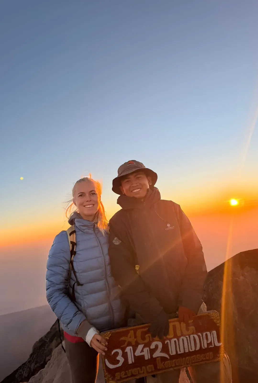 Local Mount Agung guide and trekker at sunrise with the 3142 MDPL sign