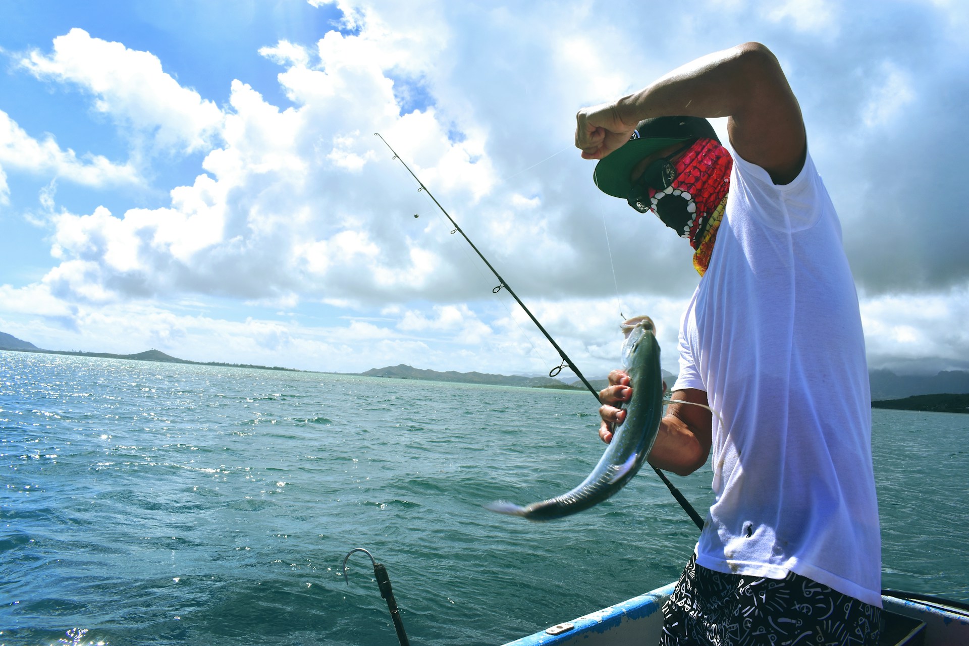Angler on a boat bending a rod into a fish over open tropical water