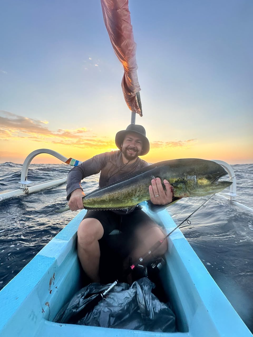 Angler on a boat bending a rod into a fish over open tropical water