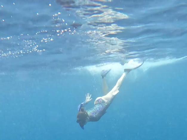 Traveler snorkeling above coral reefs in Amed