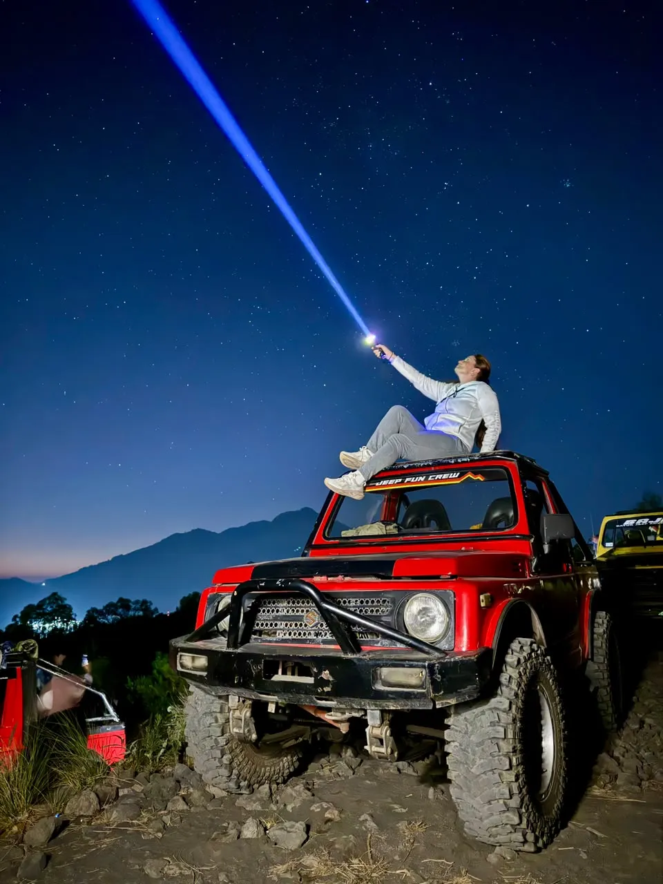 Red jeep on rocky ground under the stars