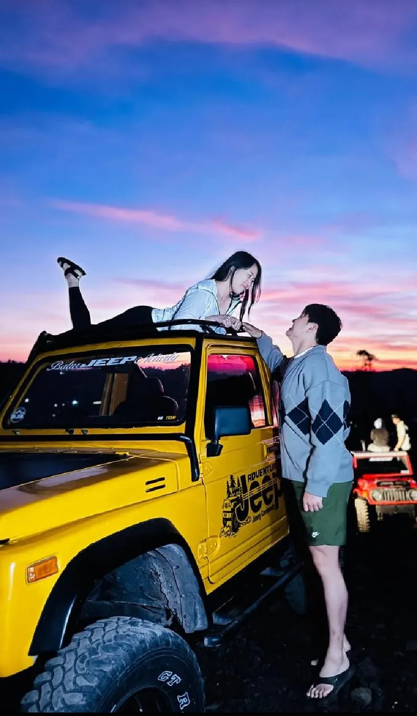 Guests posing with a yellow jeep as the sky turns pink
