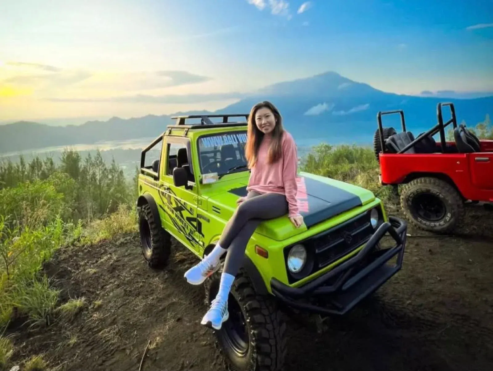 Guest on a green jeep with Mount Batur and the caldera behind