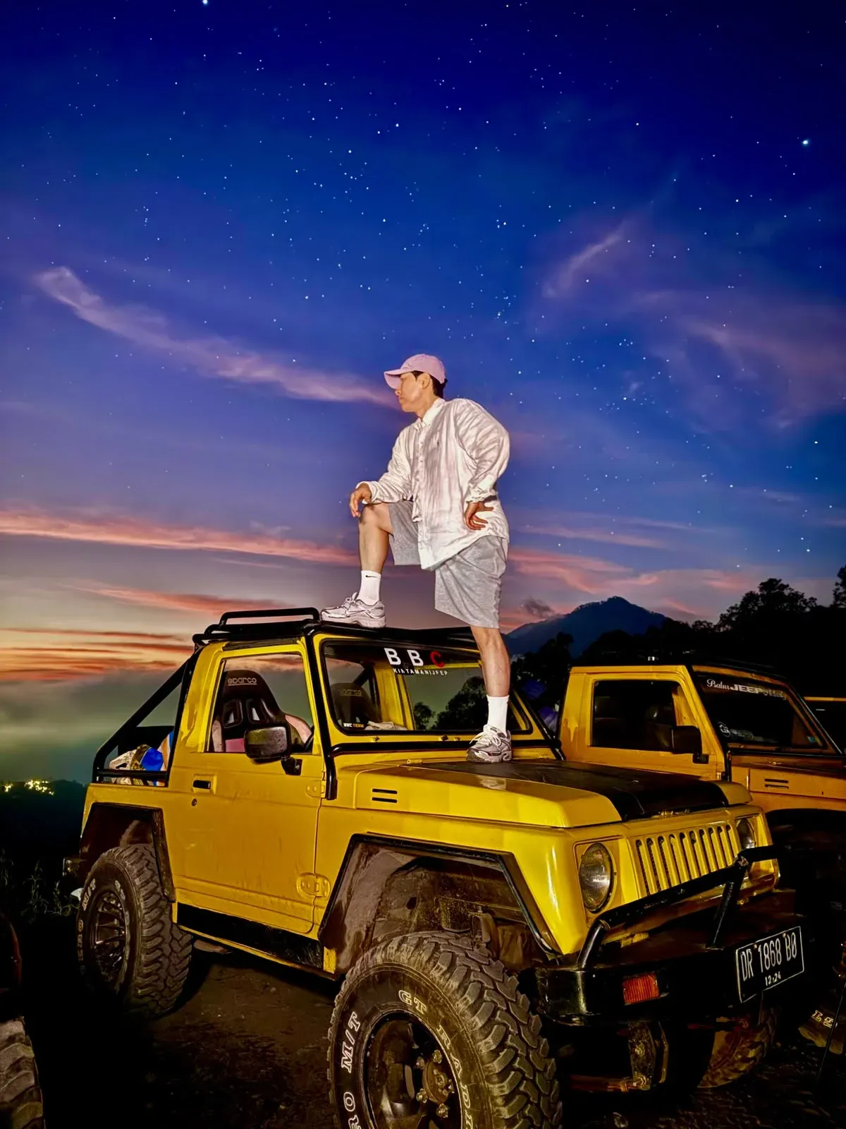 Guest standing on a yellow BBC jeep under a starry pre-dawn sky