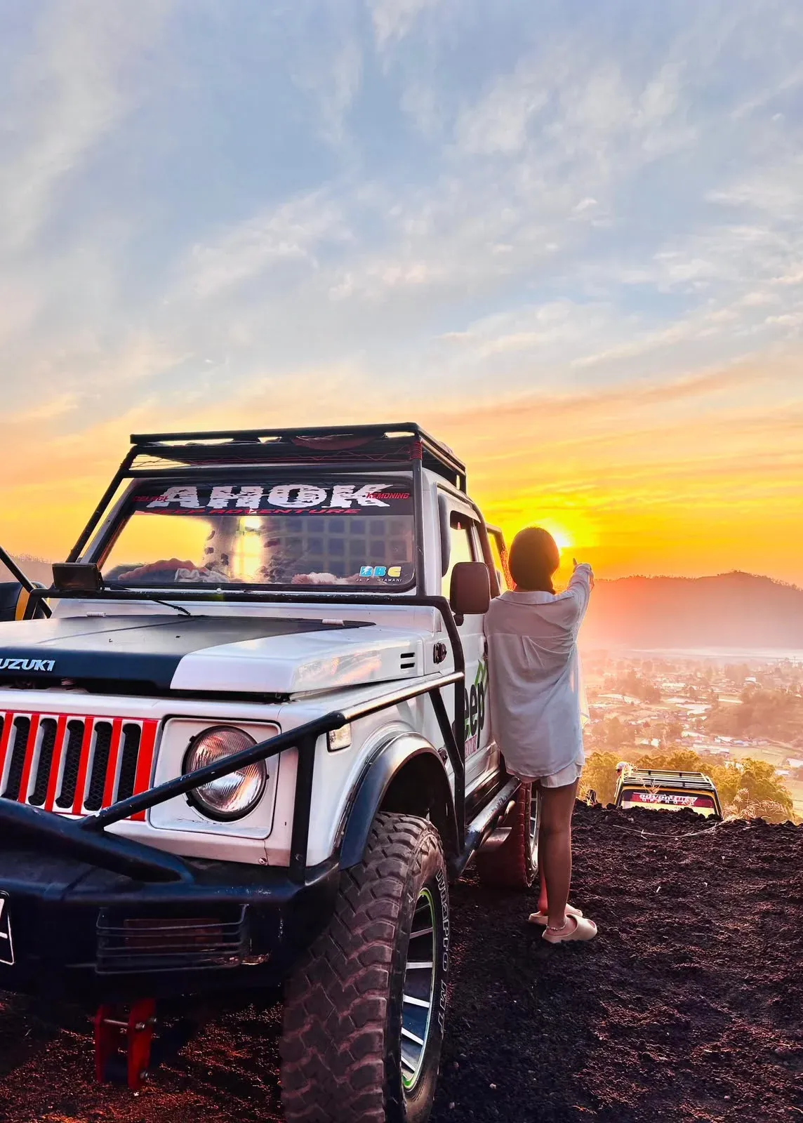 Guest beside a white 4WD jeep as the sun rises over the Kintamani ridge