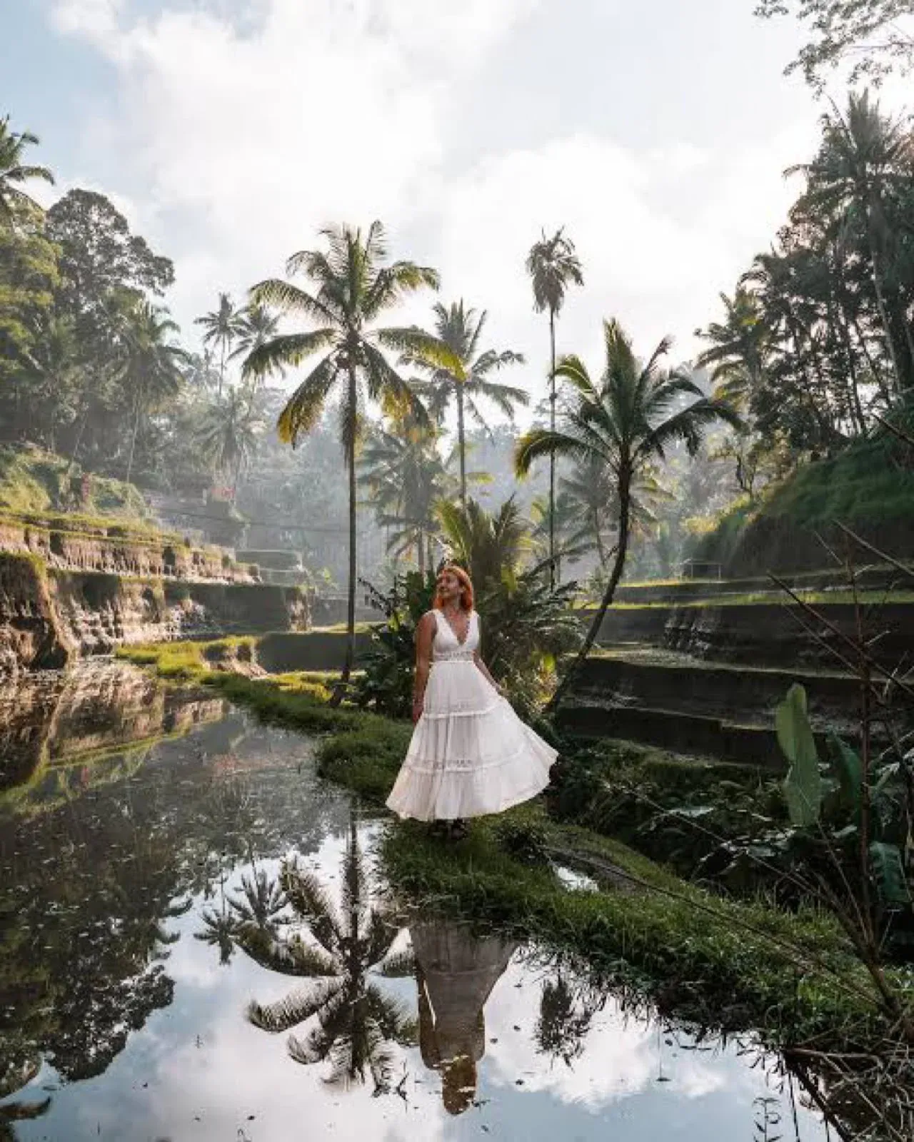 Guest in a white dress beside a reflecting pool in the rice terraces