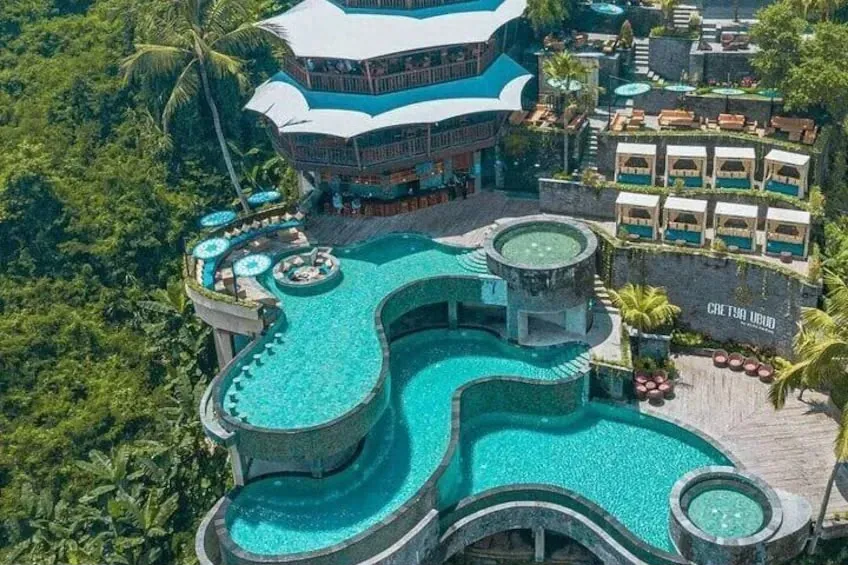 Aerial view of turquoise pools and cabanas at Cretya Ubud, with the name on the stone wall