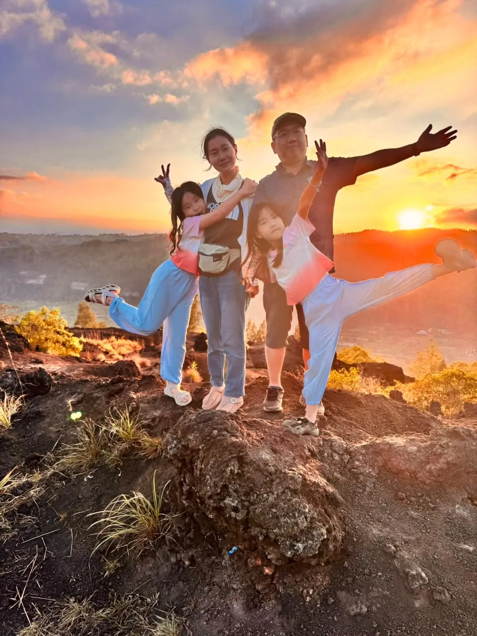 A family posing on volcanic rock as the sun sets over the ridge
