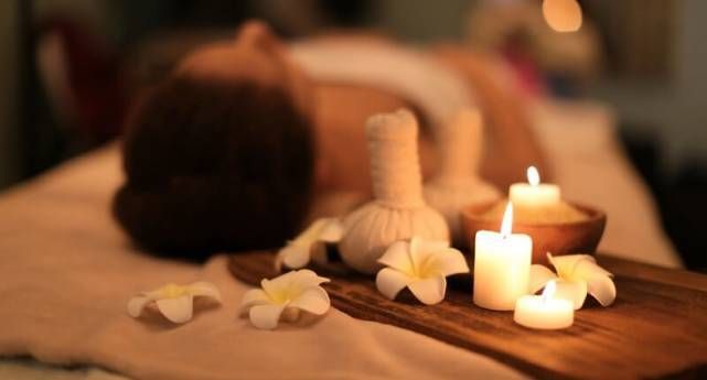 Ruang spa hangat dengan tempat treatment, handuk putih, dan cahaya lembut
