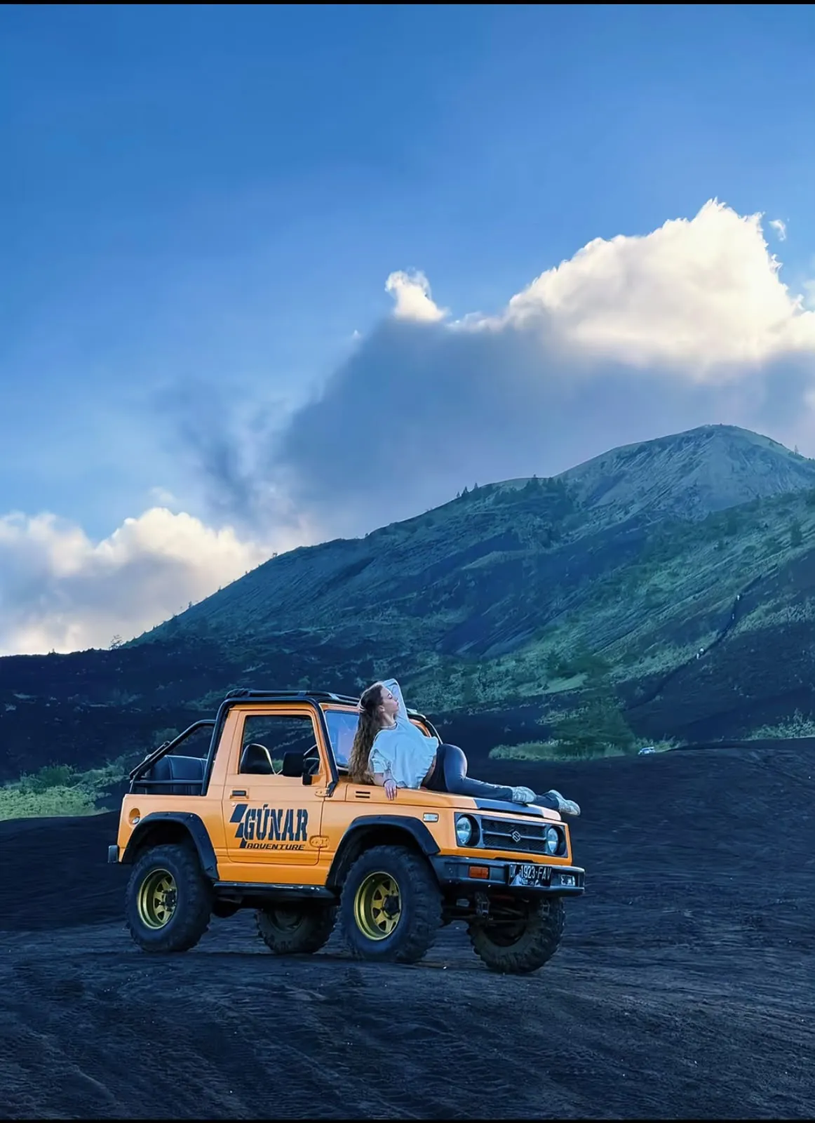 A 4x4 jeep on the black lava of Mount Batur at sunrise.