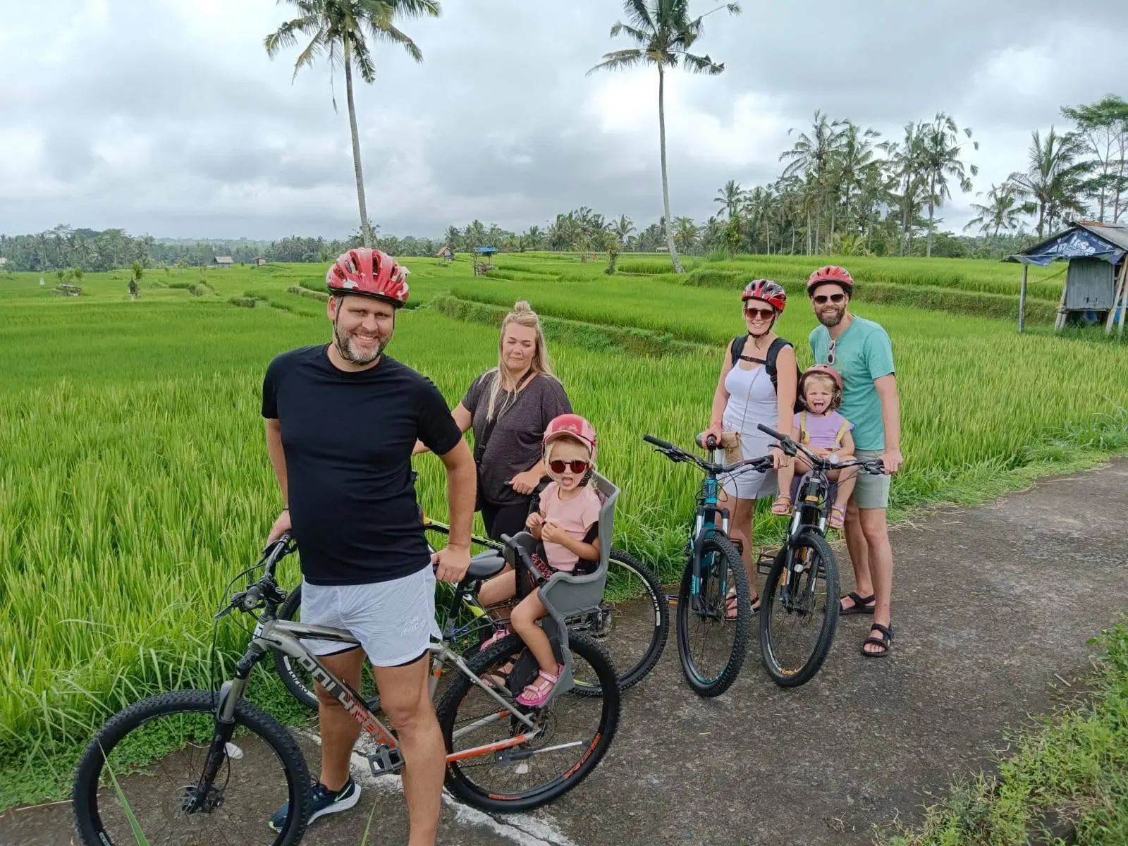 Family cycling beside Bali rice fields