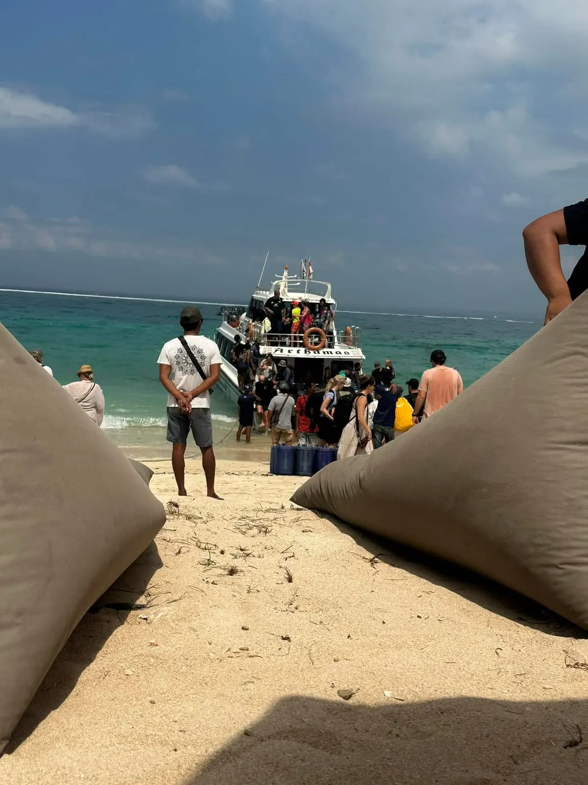 Passengers meeting a boat on a sandy Gili beach