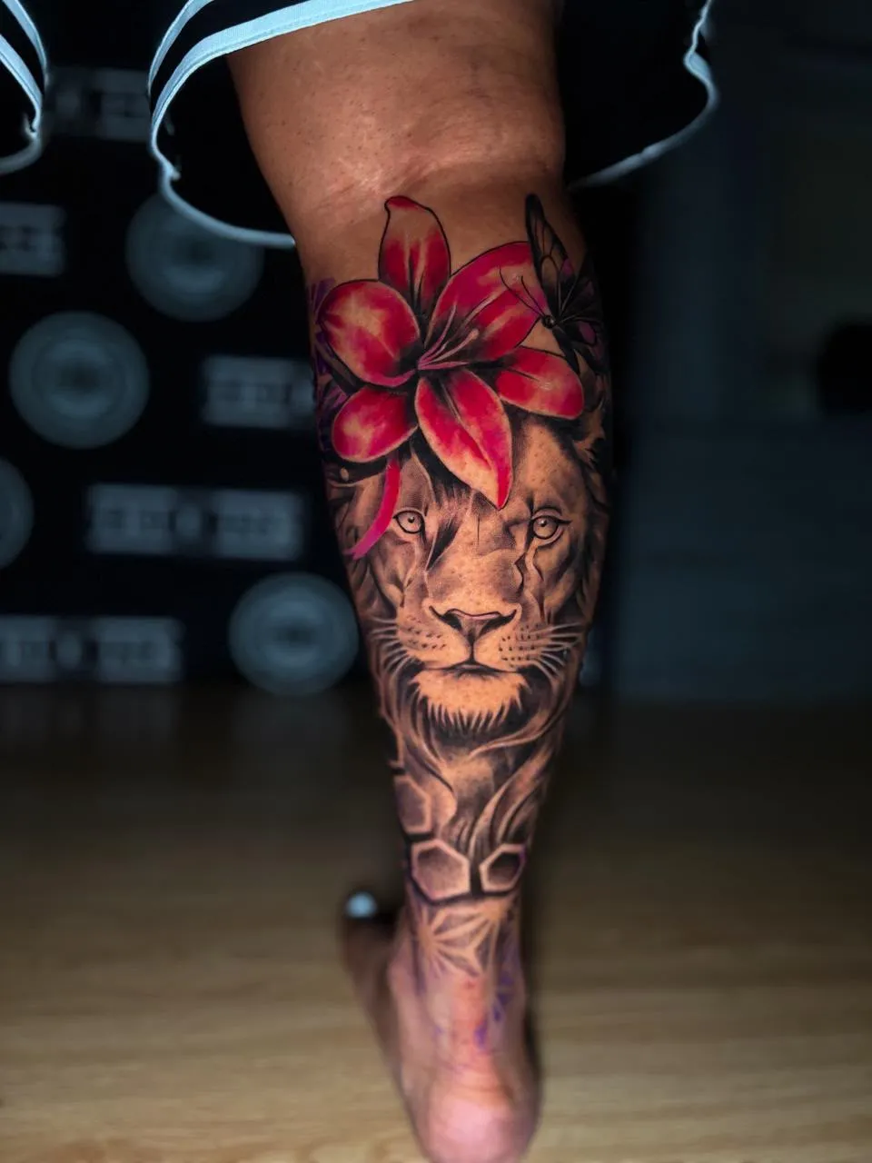 Lion and red lily tattoo running down the calf