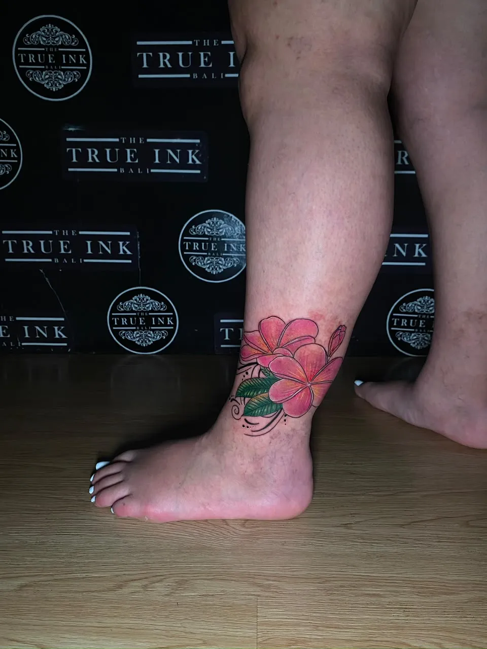 Colour frangipani flowers tattooed around the ankle