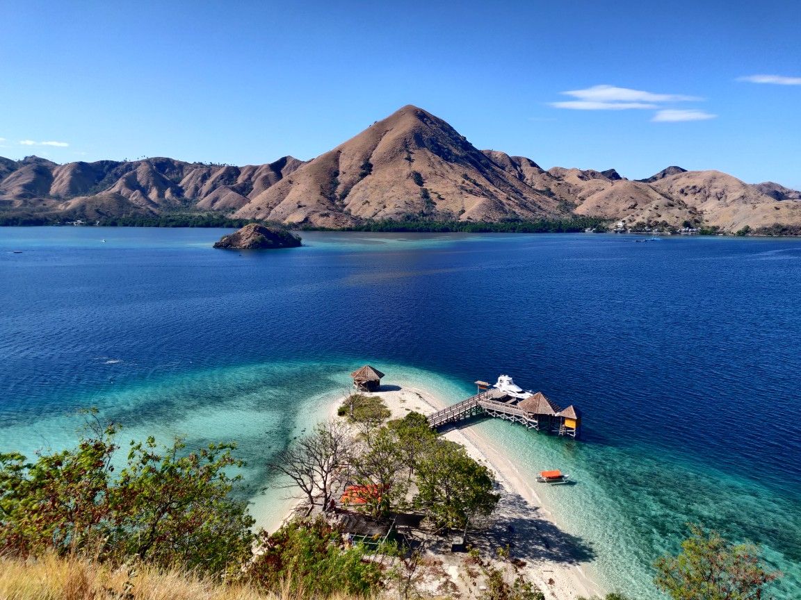 Bukit hijau kecil di tepi pantai berpasir putih