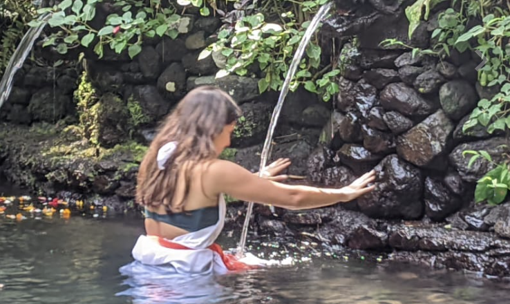 Holy spring water spouts filling a stone purification pool in Bali