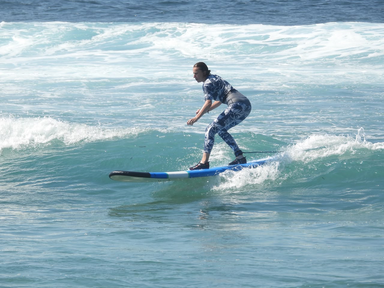 Smiling surf student carrying a board on a Bali beach