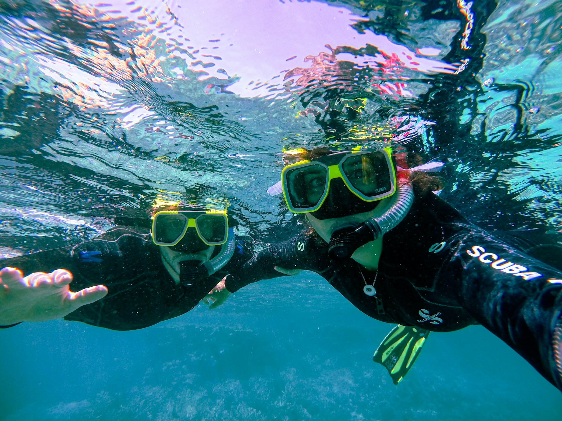 Snorkeler descending toward a sunlit coral reef