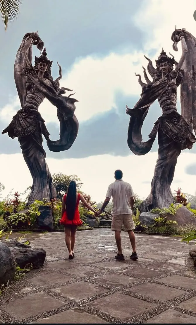 Couple walking toward giant Balinese dancer statues