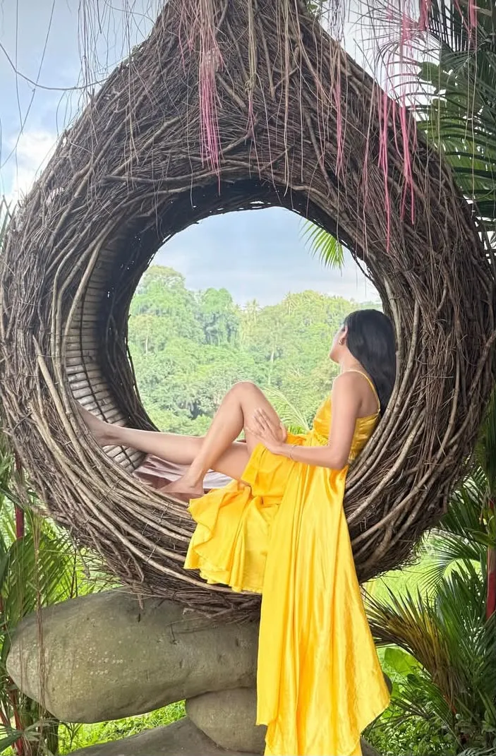 Guest in a yellow dress seated in a nest chair, Ubud