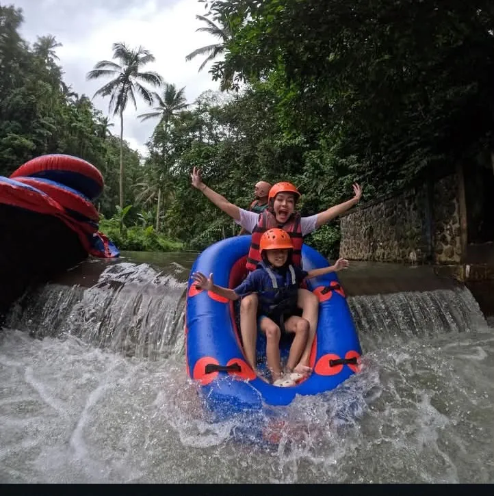 Family dropping a small waterfall while river tubing
