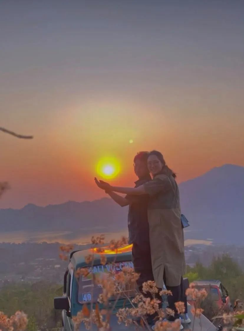 Couple on a jeep at sunrise overlooking Lake Batur