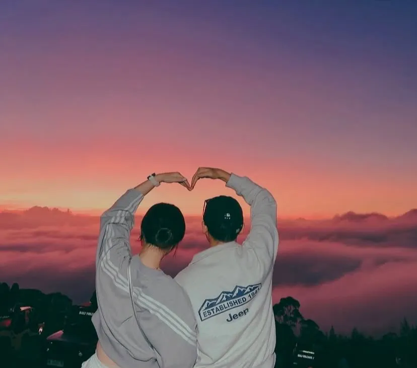 Couple making a heart over the sea of clouds at sunrise