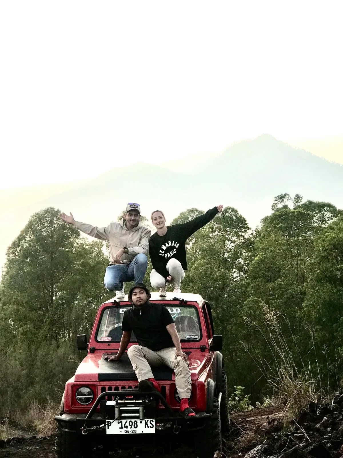Guests on a red jeep with Mount Batur behind them