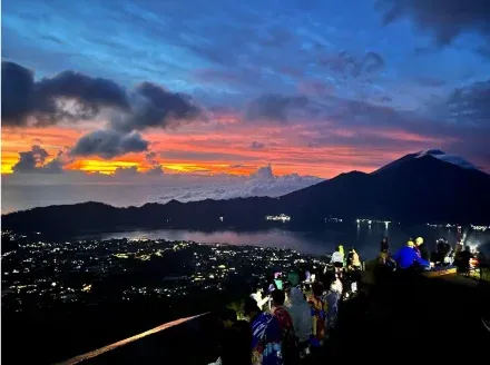 Trekkers on the rim before sunrise, town lights in the caldera below