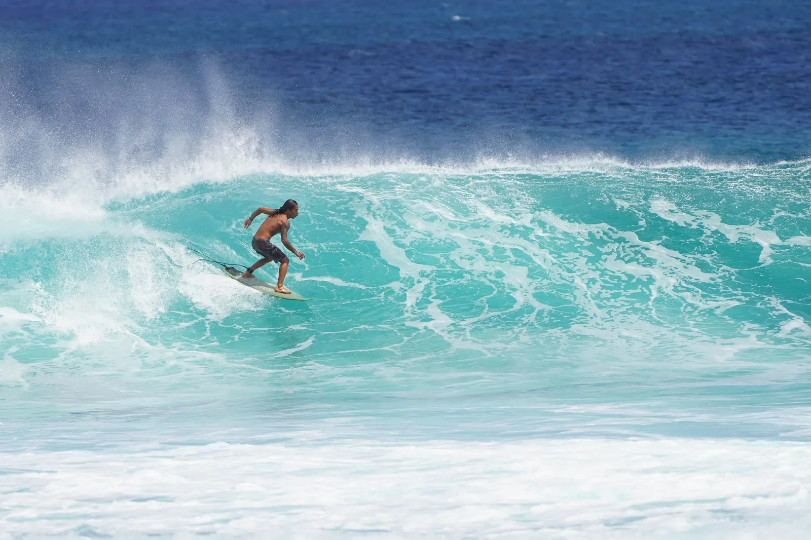 One surfer riding alone down a turquoise wave