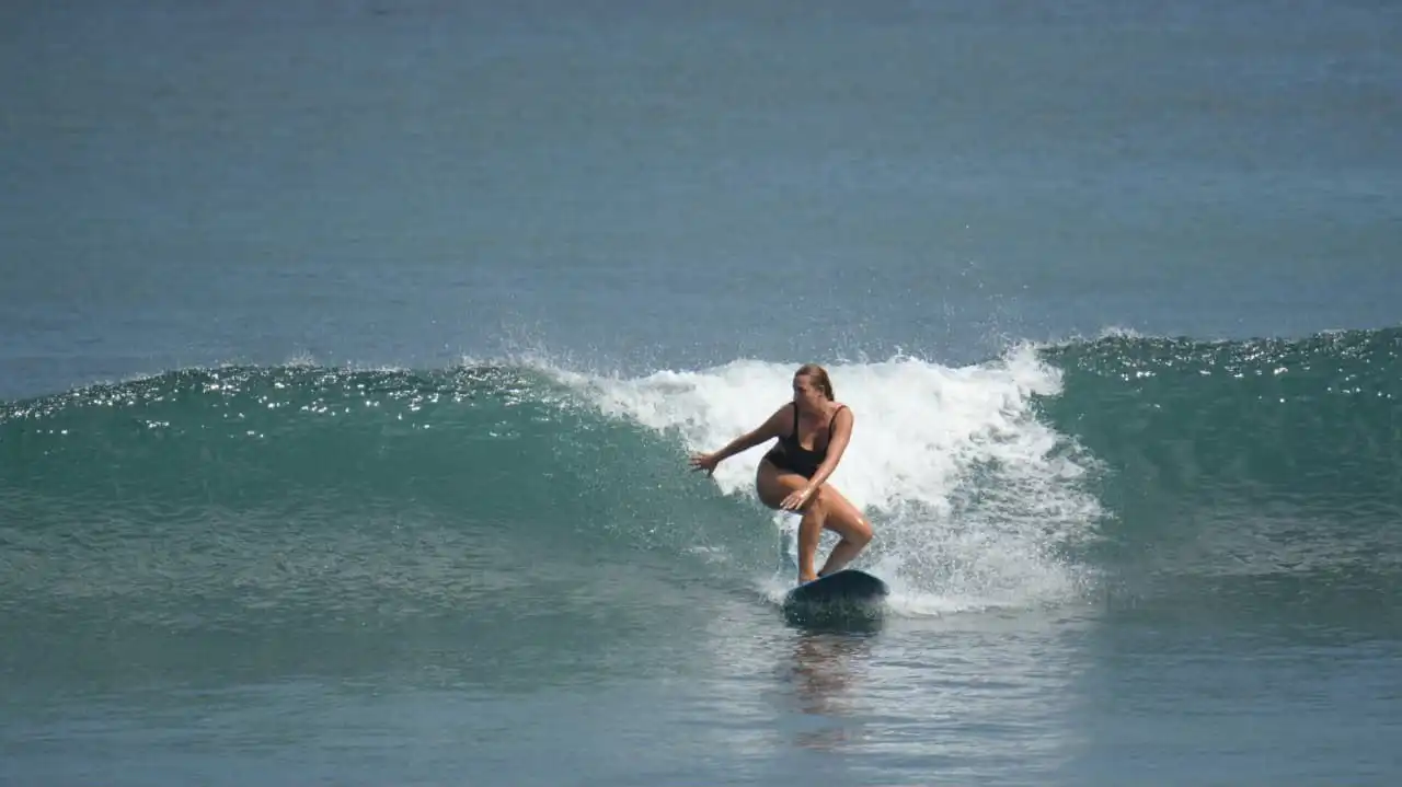 Instructor carrying a white surfboard on the sand