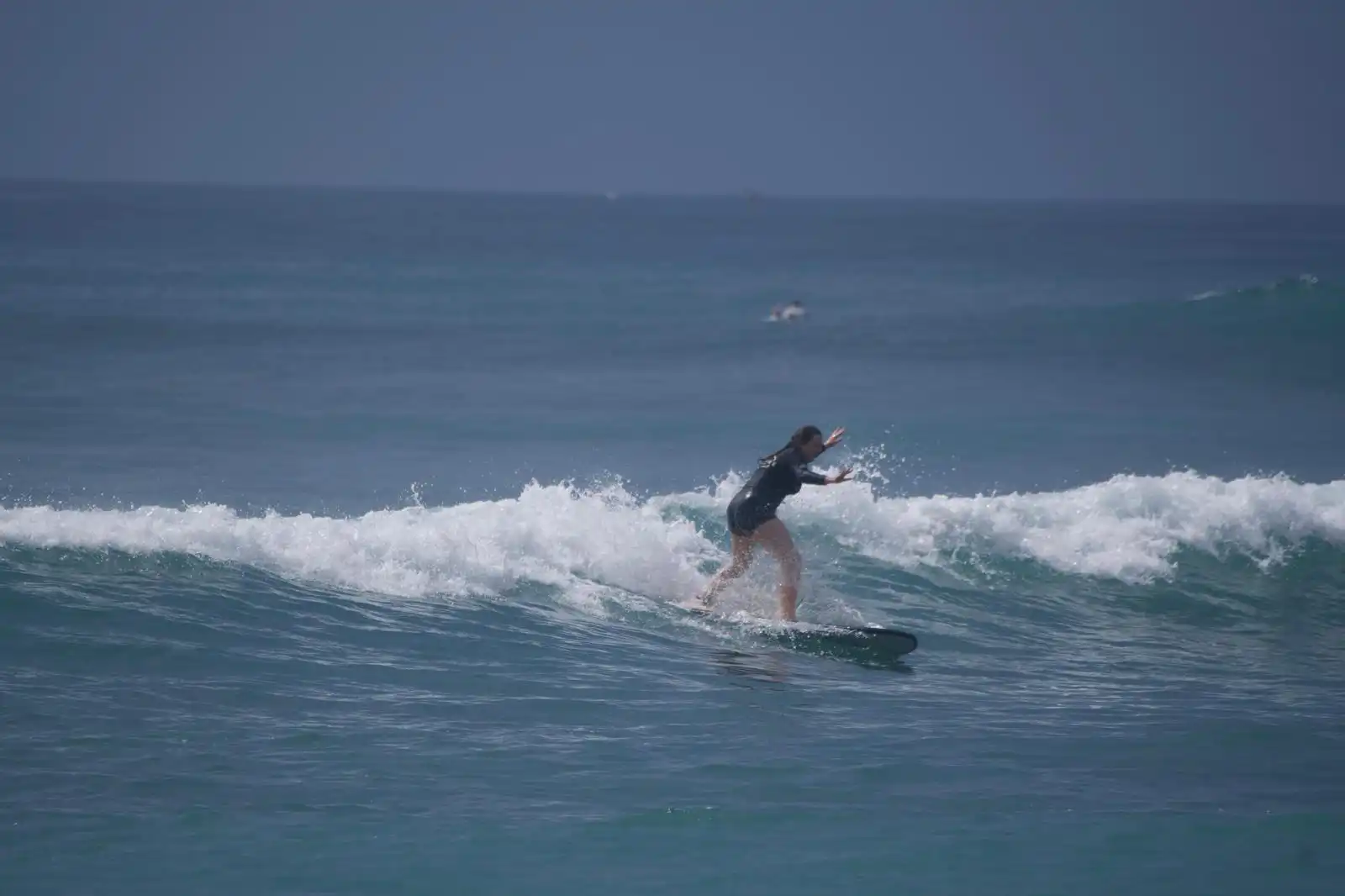 Student surfing with an instructor watching nearby