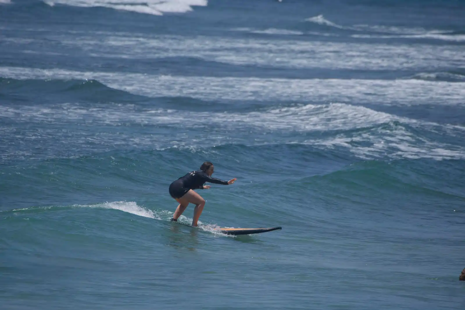 Surfer riding whitewater with other students nearby