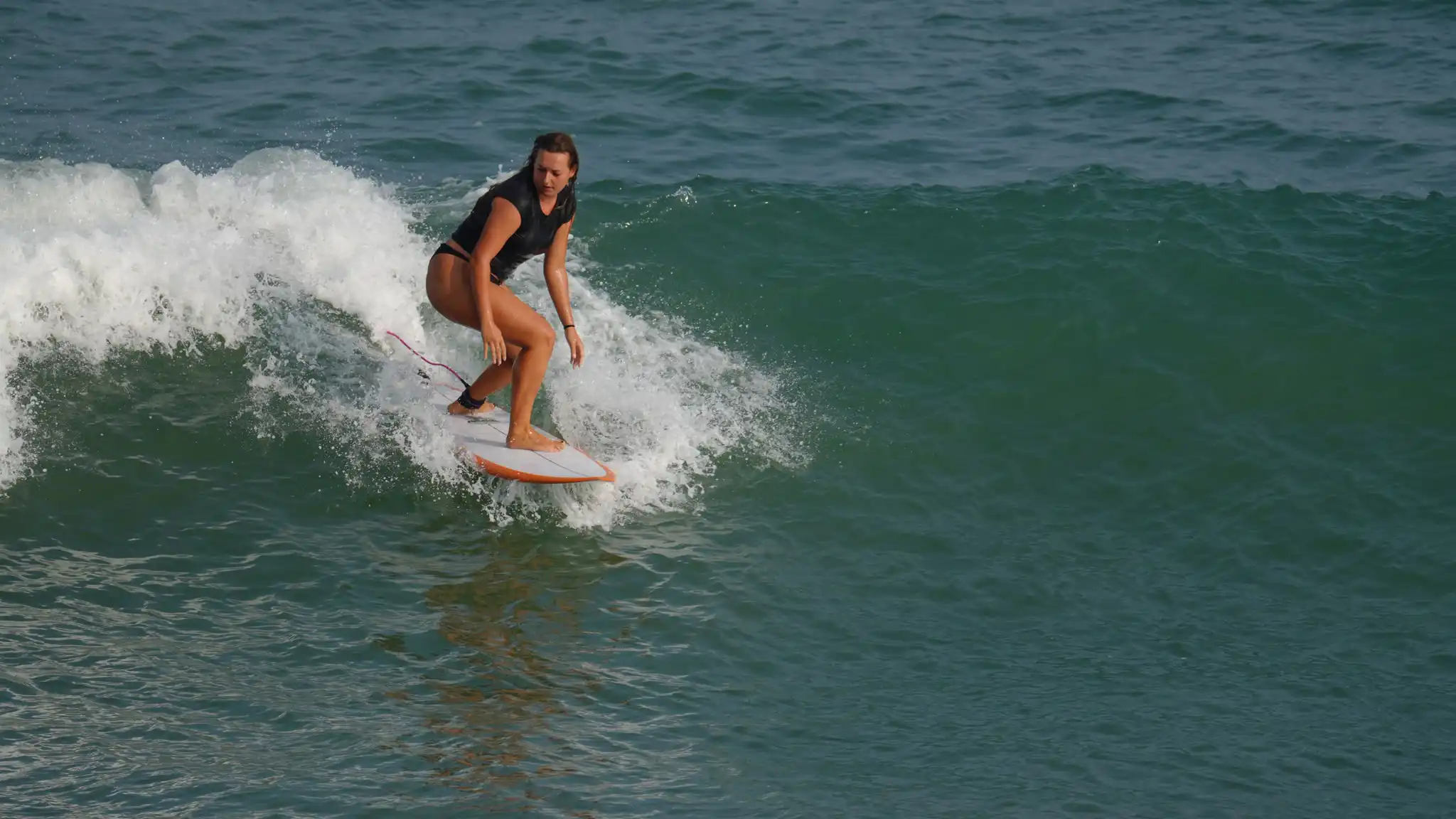 Surfer crouched low on a breaking wave