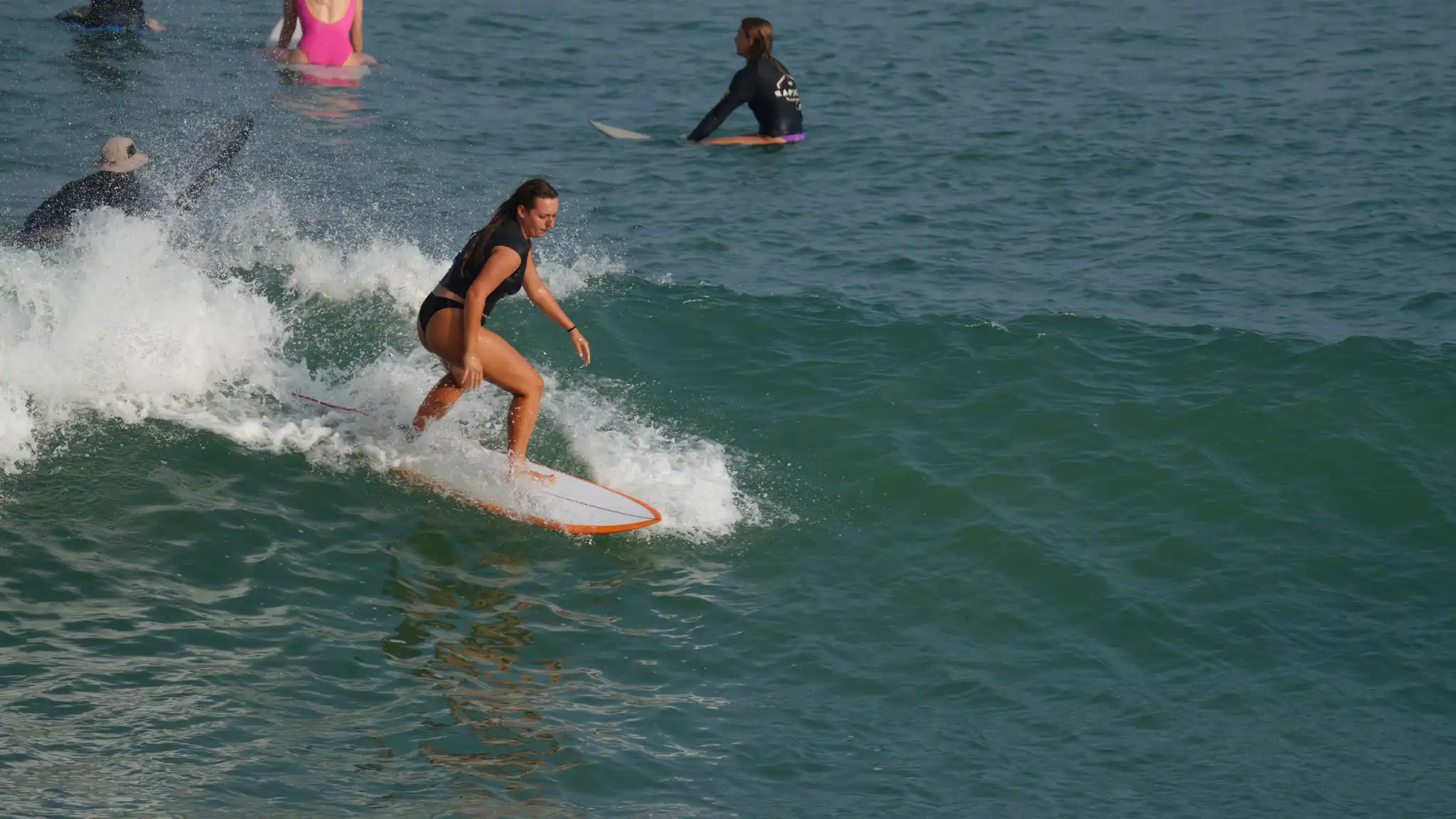 Student surfing past whitewater on an orange board